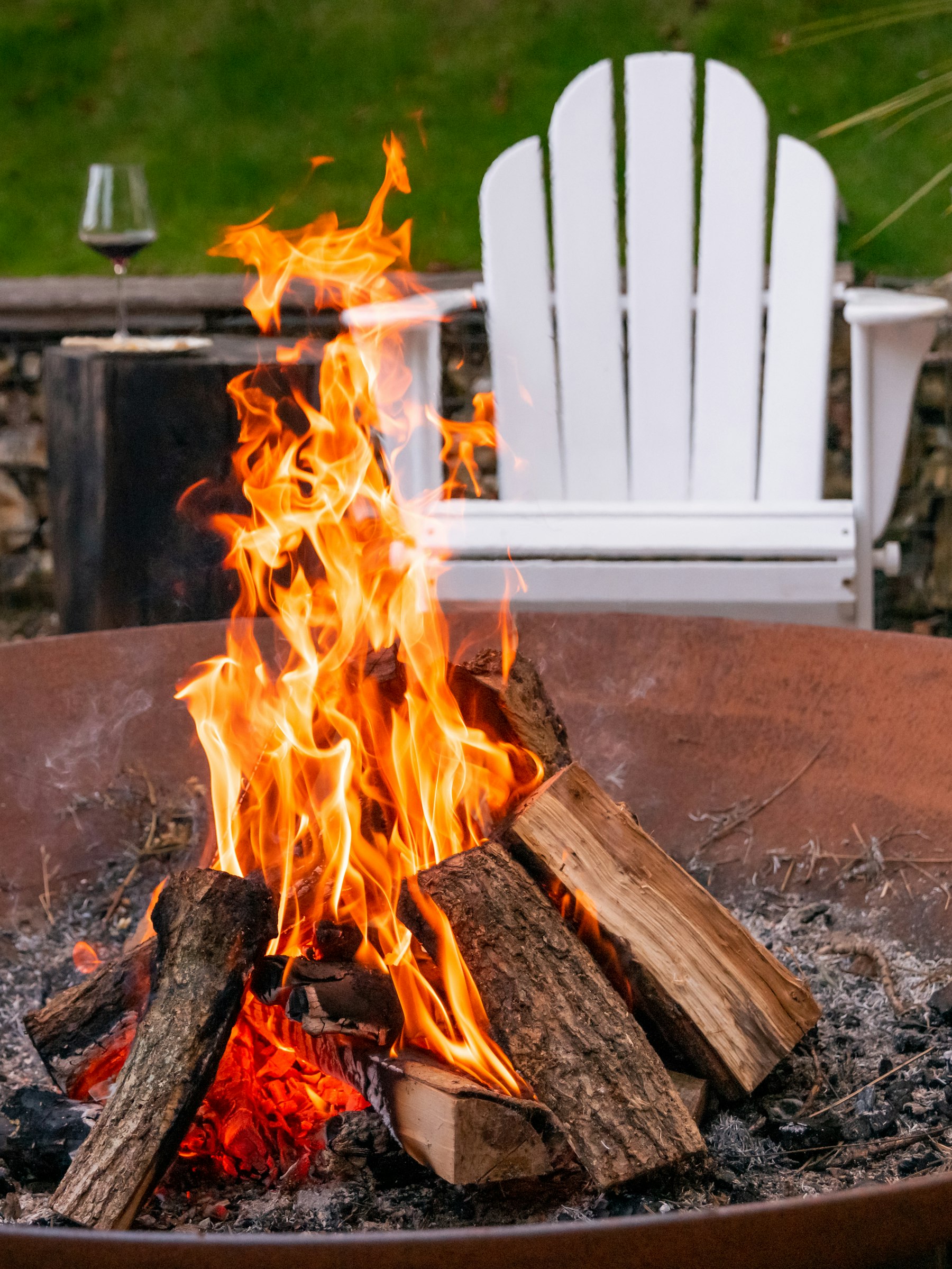 Warm outdoor evening scene with fire pit and Adirondack chair